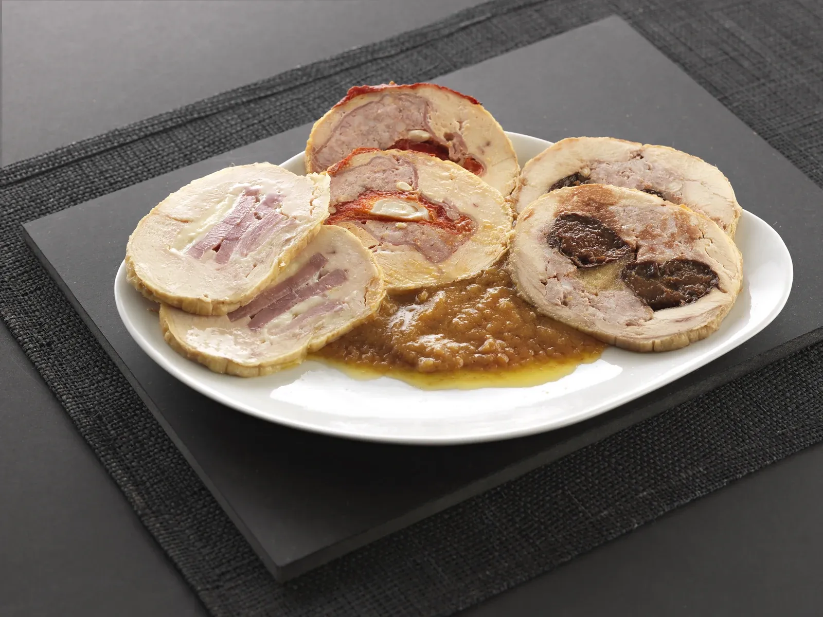 Rodanxes de carn farcida, de tres farcits diferents, un amb pebrot vermell i un altre amb prunes, servides amb salsa