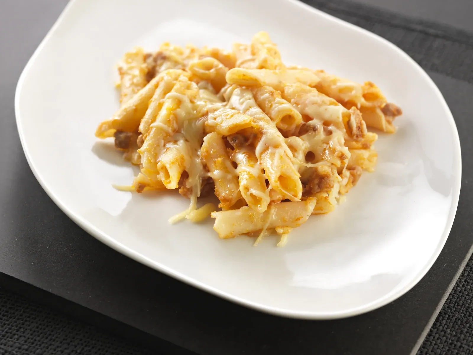 Macarrons amb carn picada, gratinats amb formatge, en un plat blanc