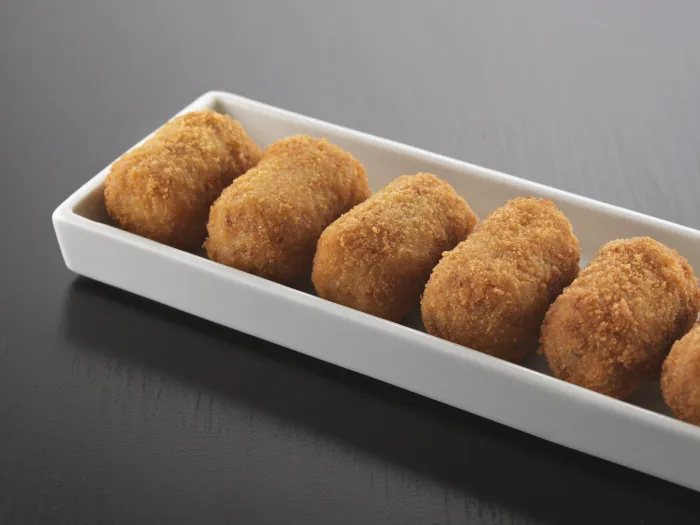 Croquetes daurades i arrebossades, arrenglerades en una safata blanca allargada