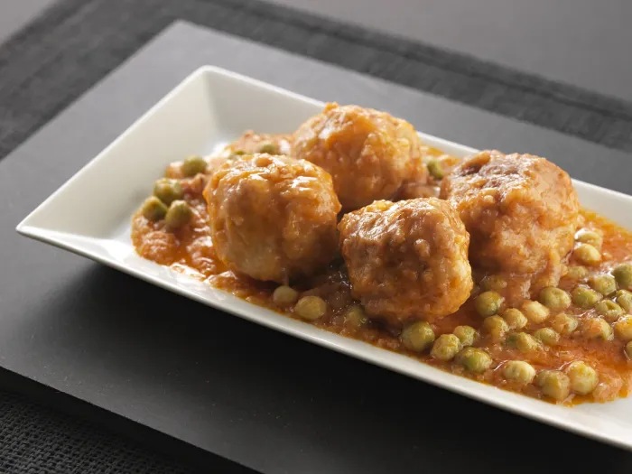Mandonguilles amb pèsols i salsa, servides en una safata blanca